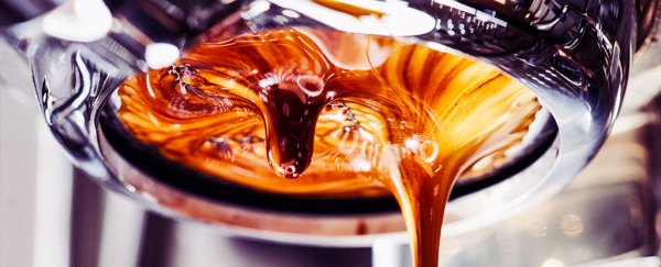 Close up of espresso coming out of machine, a rich brown-orange color.