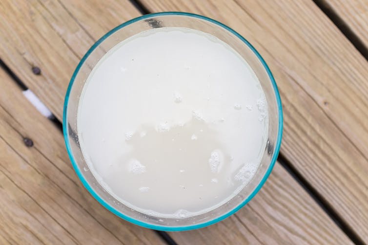 A birds-eye view of a glass of cloudy water on a table.