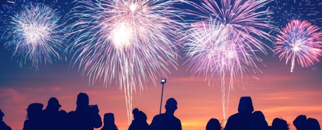 People standing at sunset looking at fireworks