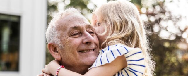 A young girl kissing an elderly man on the cheek