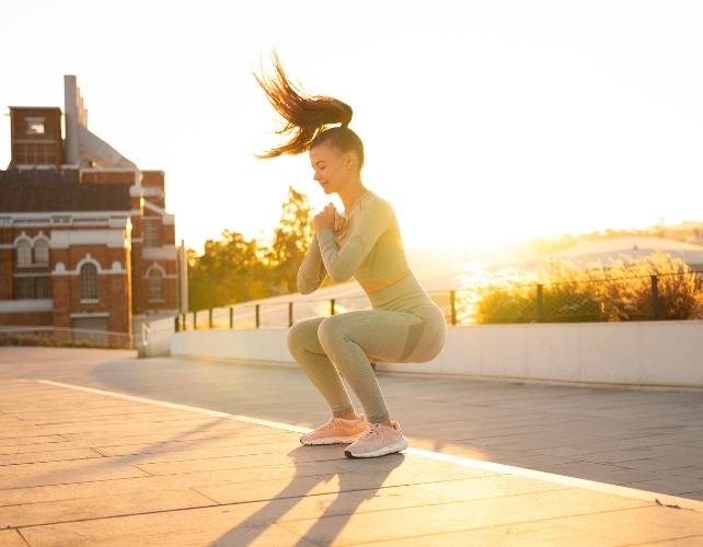 A women squatting on a sidewalk in the sun