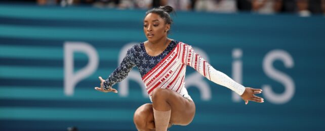 A gymnast with a Paris sign behind them